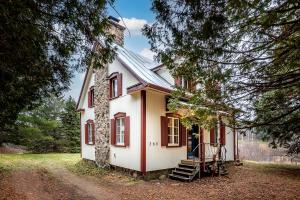 a white house with red shutters and a porch at Ancestral Wooden Chalet - St-Gabriel de Brandon in Mandeville