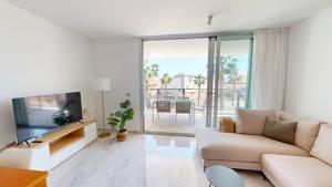 a white living room with a couch and a tv at Casa Virginia in Los Alcázares