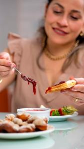 a woman eating food with a fork and a plate of food at Pousada Tia Eni in Gramado
