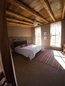 a bedroom with a bed in a room with windows at Pampachayoq - Mountain retreat in Urubamba