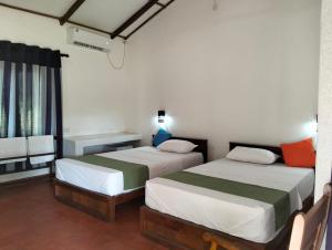 a bedroom with two beds and a window at Tiara Elephant Lodge in Habarana