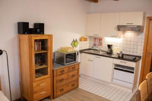a small kitchen with white cabinets and a microwave at Appartement Achtern Diek 2-23 in Dorum-Neufeld