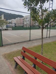 a wooden bench sitting next to a tennis court at Praia canavieiras in Florianópolis