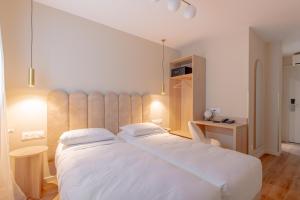 a bedroom with a large white bed and a desk at Grand Hotel Sénia - Paris Orly Airport in Orly