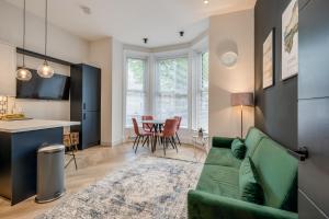 a living room with a green couch and a kitchen at Bliss Stay Belfast University Street in Belfast