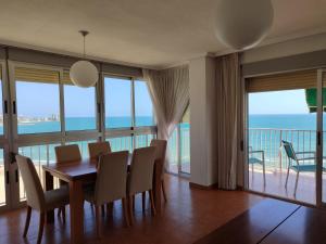 Un comedor con mesa y sillas y el océano. en Aloha frente al Mar, en Cullera