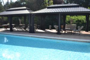 a gazebo with a table and chairs next to a pool at Traditional Log Cabin next to Harry Potter Studios in Kings Langley
