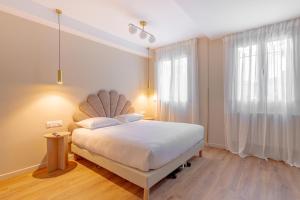 a bedroom with a white bed and a large window at Grand Hotel Sénia - Paris Orly Airport in Orly