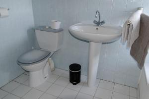 a white bathroom with a toilet and a sink at Hotel Du Commerce in Pont-Saint-Esprit