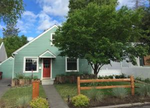 a green house with a red door and a tree at Bluebird Day - Hill Street Beauty in Bend