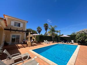 a swimming pool with chairs and a house at Perfect Golf & Beach Villa for 8 people in Estômbar