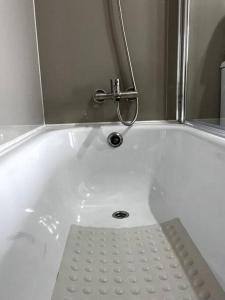 a white bath tub with a metal shower istg at Departamento Mono - Ambiente in Osorno +14 photos