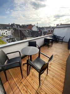 ein Balkon mit Stühlen und Tischen auf einem Dach in der Unterkunft Oldtown Apartment Andreasstrasse in Düsseldorf
