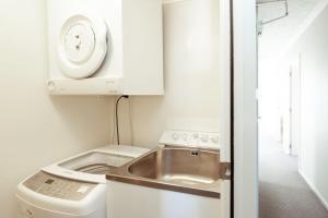 a small kitchen with a sink and a washing machine at Central Methven 3-Bedroom Apartment in Methven