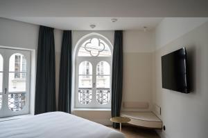 a bedroom with a bed and a tv and a window at Hôtel du Sentier in Paris
