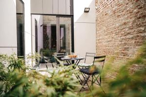 a patio with a table and chairs and a brick wall at Appart'24 Cosy au centre de Huy in Huy