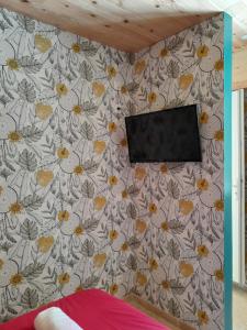 a tv on a wall with a floral wallpaper at Love-Room Spa de la TRUFFIERE in Bertric-Burée