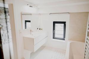 a white bathroom with a sink and a mirror at Appart'24 Cosy au centre de Huy in Huy +35 photos