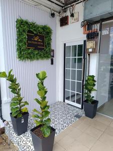 a sign on the side of a building with potted plants at Alameen Boutique Hotel in Kangar