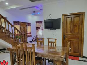a dining room with a table and a flat screen tv at Villa Thaarhai in Jaffna