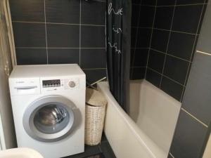 a washing machine in a bathroom next to a bath tub at Apartamenty na doby in Siedlce