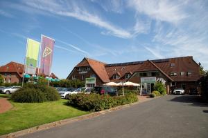 a building with cars parked in a parking lot at Cuxlandhotel Doppelzimmer 120 in Dorum-Neufeld