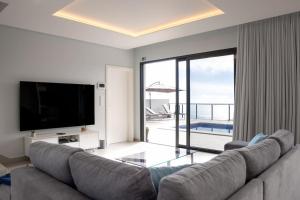 a living room with a couch and a flat screen tv at Vila Indigo in Arco da Calheta