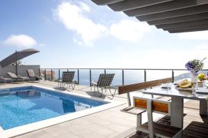 a balcony with a pool and a table and chairs at Vila Indigo in Arco da Calheta