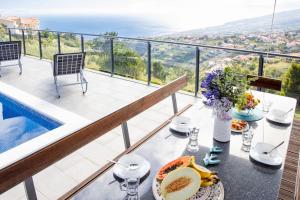 a table with food and flowers on a balcony at Vila Indigo in Arco da Calheta