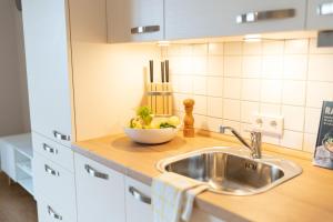 a kitchen counter with a sink and a bowl of vegetables at Gemütliche Sonnenwohnung am Meer mit Sauna in Cappel-Neufeld