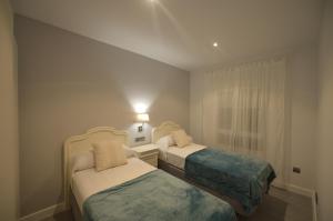 Cette petite chambre comprend 2 lits et une fenêtre. dans l'établissement Apartamento Victoria, à Cadix