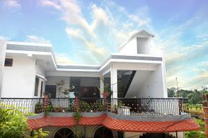 a white house with a balcony with a fence at Khajuraho Glory Homestay in Khajurāho