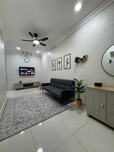 a living room with a couch and a tv at Namel Homestay Taiping in Kampong Jana