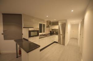 une cuisine avec des placards blancs et un comptoir noir dans l'établissement Apartamento Victoria, à Cadix