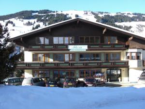 a large building with cars parked in front of it at Hotel-Pension Flora in Saalbach Hinterglemm