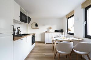 eine Küche mit einem Tisch und Stühlen sowie eine Küche mit weißen Schränken in der Unterkunft Ferienhaus Ahorn, wunderschöne, neue Wohnungen, ideal für Ausflüge ins Phantasialand, die Städte Köln, Brühl und Bonn oder die Eifel in Weilerswist