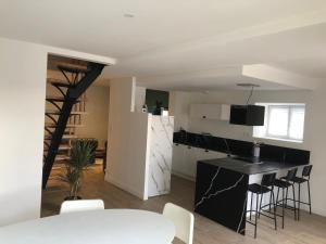 a kitchen and living room with a black counter and chairs at Charmante maison in Château-Gontier