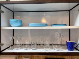 a shelf filled with glasses and blue dishes on it at Studio Apartment, close to beach and sunset views in Umm Al Quwain