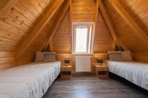 two beds in a wooden attic room with a window at Ferienhaus Mellumplate 52 in Dorum Neufeld