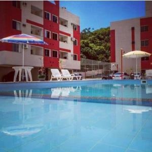 a swimming pool with an umbrella and a building at Apê da Gabi in Balneário Camboriú