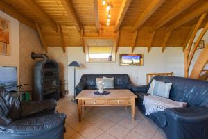 ein Wohnzimmer mit Ledersofas und Holzdecke in der Unterkunft Ferienhaus "Familie Haupt" Mellumplate 48 in Dorum Neufeld