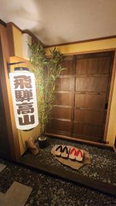 ein Zimmer mit einer Pflanze und zwei Paar Schuhen in der Unterkunft Hida Takayama Kandamachi House - Vacation STAY 88763v in Takayama