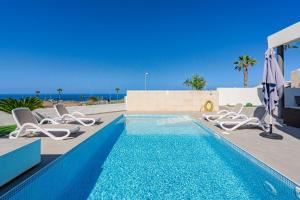 Una piscina con tumbonas y el océano. en Villa Caterina, Luxury Villa with Heated Pool Ocean View in Adeje, Tenerife, en Adeje