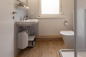 a bathroom with a sink and a toilet and a window at Ferienhaus Vogelsand 08 in Dorum-Neufeld +34 photos