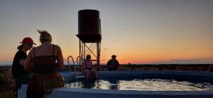 a group of people standing around a pool with a water tower at Willem Sternbergwa Adam se Uitspanning in Orania