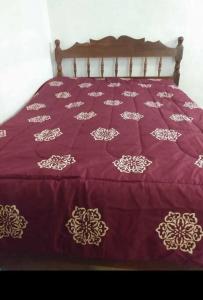 a bed with a purple comforter with gold designs on it at Casa Sótano, con alberca in Las Delicias +27 photos