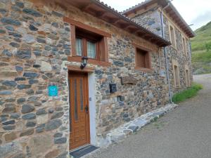 a stone house with a wooden door and windows at Casa Aires de Pajares in Camplongo