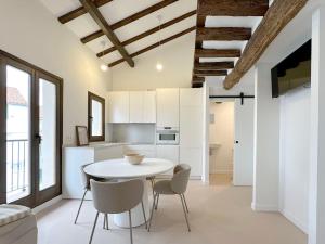 a white kitchen with a white table and chairs at Duplex con vistas a Santa María in Castro-Urdiales