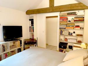 a bedroom with a bed and a flat screen tv at Maison de charme d'Ile de France in Chaumontel