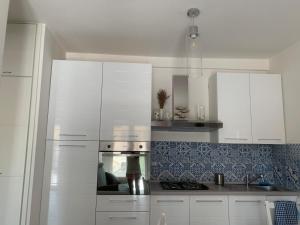 a kitchen with white cabinets and a stove top oven at Appartamento Massimo in Nettuno +5 photos